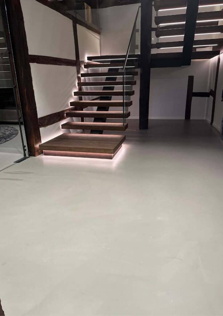 beleuchtete Treppenstufen in einem Hau mit einem Boden in Betoptik.