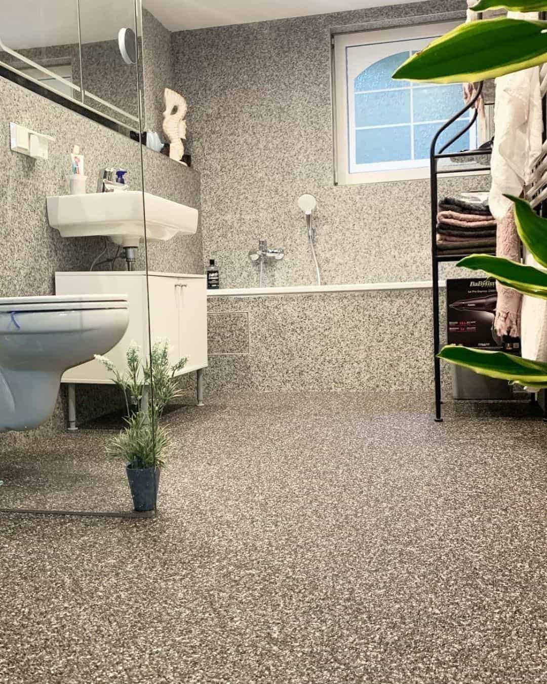 Kleines Badezimmer mit hellgrauem Steinteppich an Wand und Boden, sowie Badewanne.