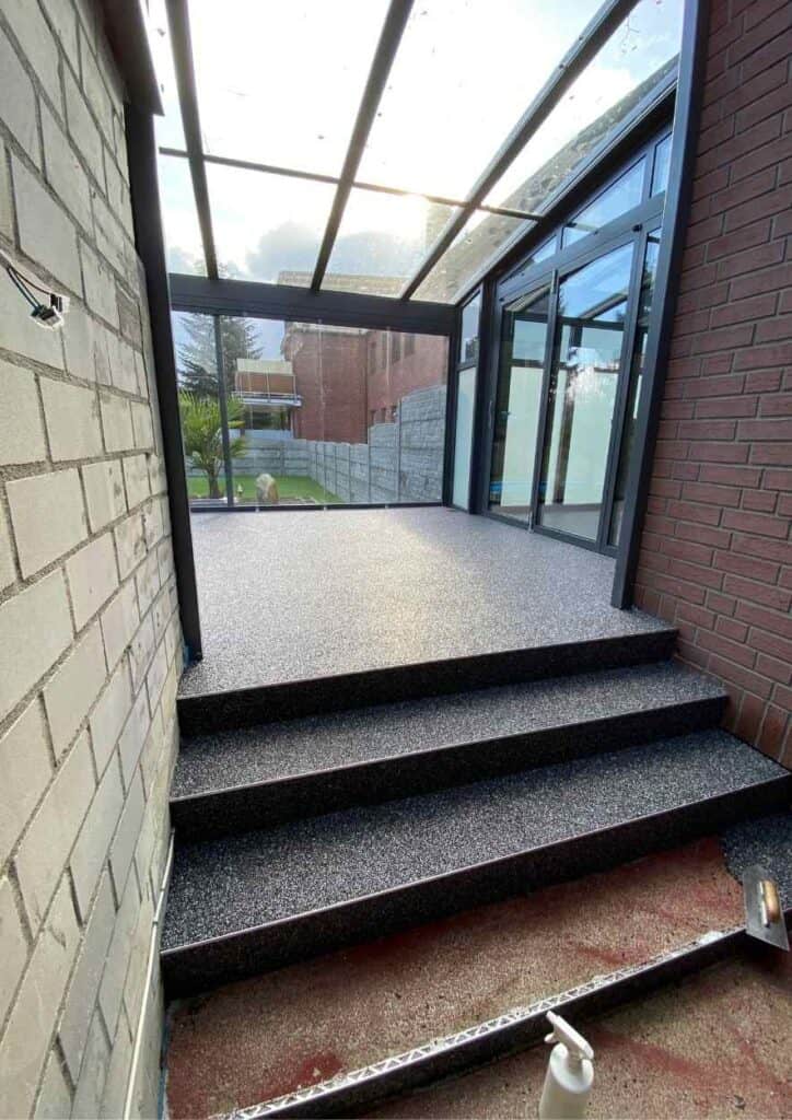 Eingang zu einer ueberdachten Terasse aus Steinteppich.