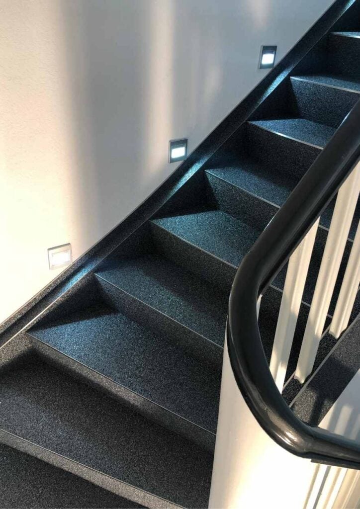 Home 11 Schwarze Steinteppichtreppe mit einem weißen Holzgelaender.