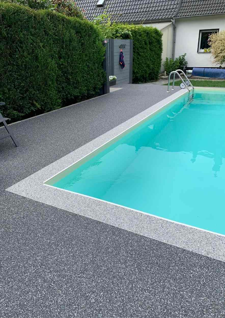 Steinteppich am Pool als graue Poolumrandung