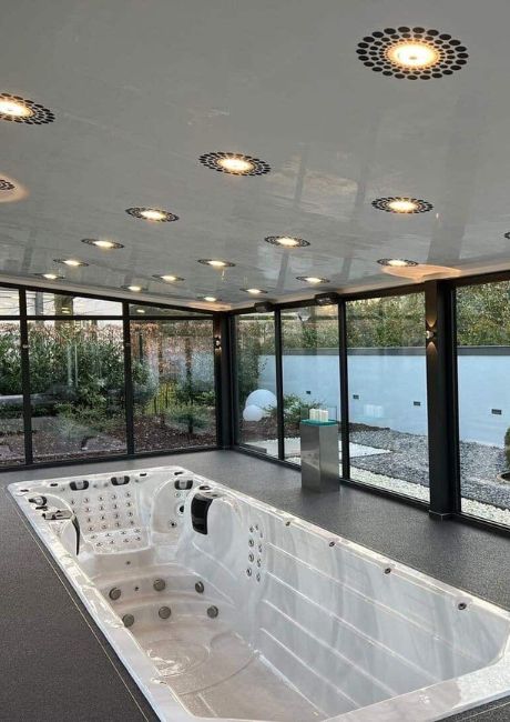 Steinteppichumrandung von einem Whirlpool in einem Wintergarten.