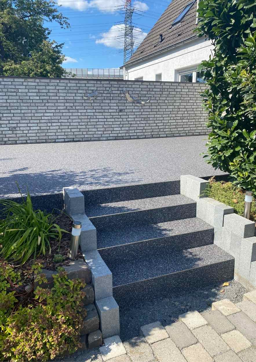 Treppenaufgang zu einer Terrasse in Steinteppichoptik.